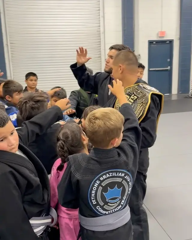 Coach Alex Avalos holds up his 559 Fight championship belt, surrounded by kids from his class.