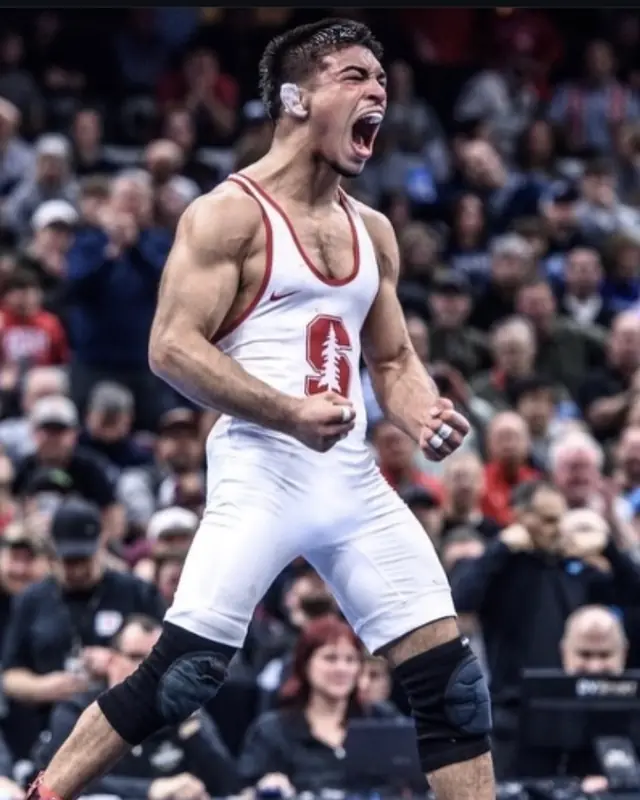 Aden Valencia, in a Stanford singlet, celebrates in a packed arena.