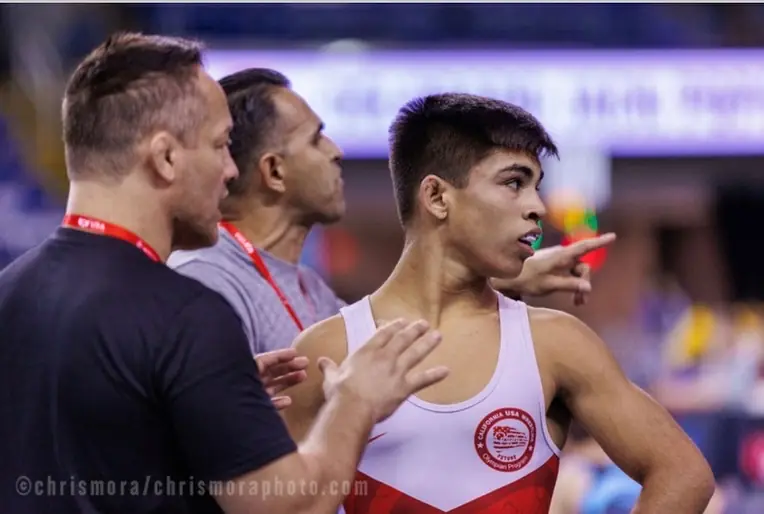 Aden Valencia, in a California USA Wrestling singlet, with two coaches at his side. Photographer’s credit: chrismoraphoto.com.