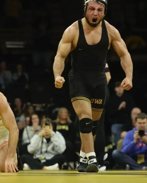Miguel Estrada, in an Iowa singlet, celebrates on the mat.